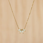 The White Opal Marquise Necklace features five marquise opal-like stones in a floral design, accented with gold and shown on a beige background.