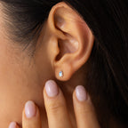 A woman’s hand gently touches her earlobe, showcasing the Pear Moonstone Studs and highlighting their delicate, celestial charm.