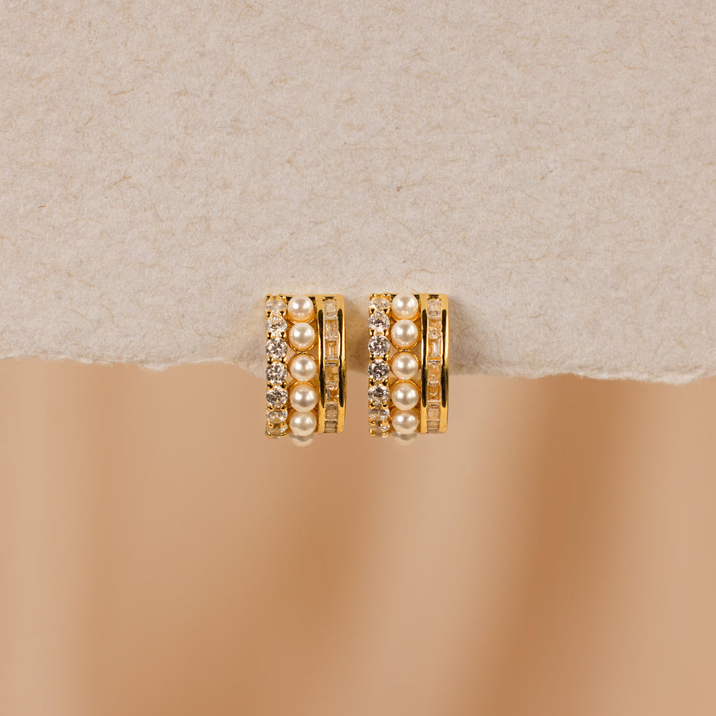 Diamond Pearl Stacked Hoops featuring rows of pearls and sparkling crystals, ideal for vintage wedding looks, showcased on a textured beige surface.