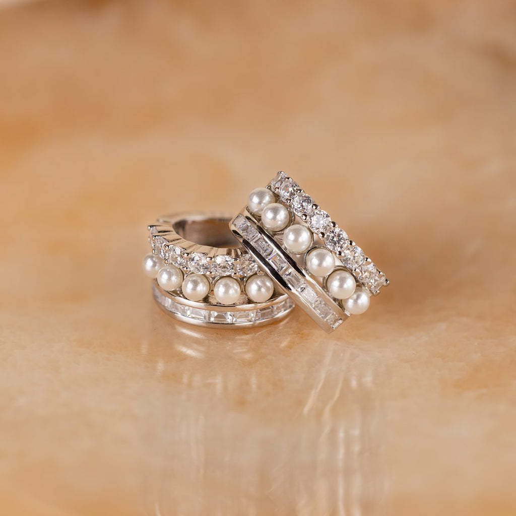 Diamond Pearl Stacked Hoops with pearls and sparkling gems rest on beige marble—ideal bridal jewelry or vintage-inspired wedding earrings for your special day.