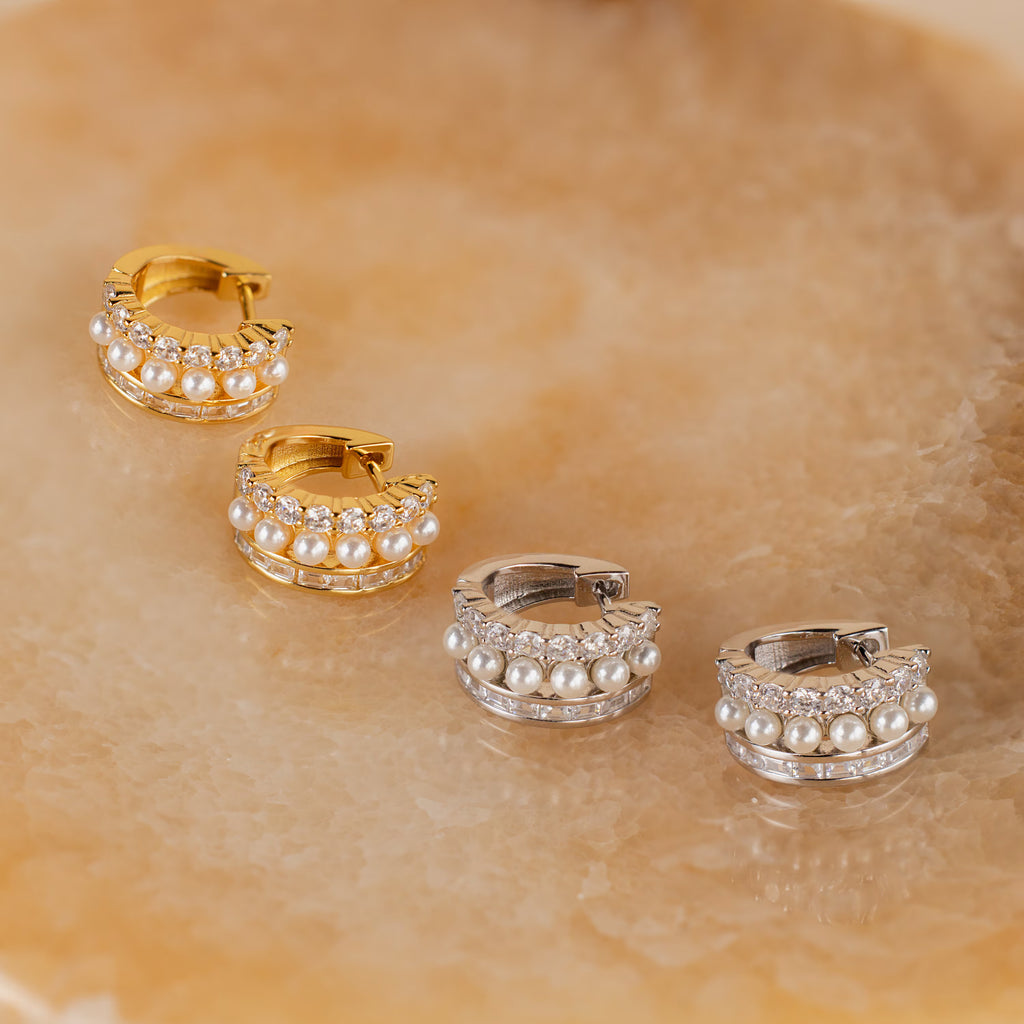Two pairs of Diamond Pearl Stacked Hoops, one in gold and one in silver, are displayed on a marble surface—perfect as elegant bridal jewelry or vintage wedding earrings.