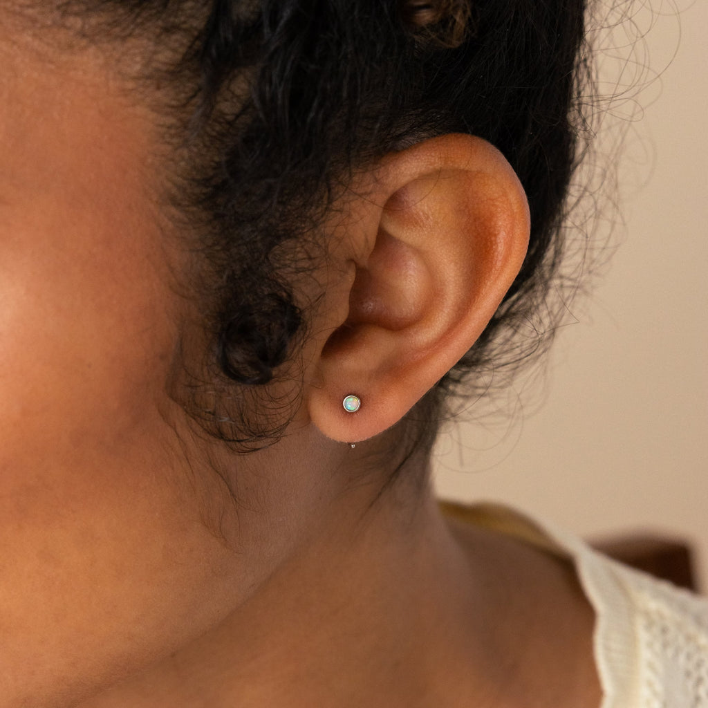 A close-up of a woman's ear wearing Opal Threader Huggies, showcasing the celestial elegance of this unique jewelry piece.