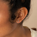 A close-up of a woman's ear wearing Opal Threader Huggies, showcasing the celestial elegance of this unique jewelry piece.