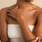 A woman in a white textured top showcases minimal style with the Curb Chain Bracelet, her hand resting elegantly on her shoulder.