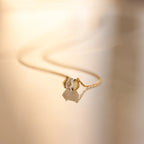 The Encased Hexagon Diamond Necklace, featuring a single diamond in a half-bezel setting, rests on a smooth, reflective surface and exudes modern sophistication.