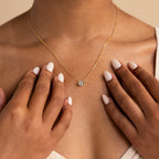 Close-up of a woman wearing the Encased Hexagon Diamond Necklace, featuring a single diamond pendant in a gold half-bezel hexagon setting, hands near her collarbone, capturing modern sophistication.