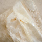 The Summer Statement Earrings Set, featuring gold lightning bolts, is displayed on a large textured white crystal—perfect for your summer look.