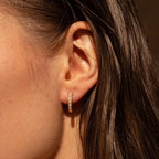 Close-up of a woman's ear wearing the Baroque Pearl Earrings Set, featuring delicate gold hoops with sparkling stones, echoing elegant baroque style, with her damp hair partially visible.
