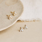 The Baroque Pearl Earrings Set, featuring gold and silver pearl studs on a ceramic plate and fabric, is ideal for mixing with baroque pearl earrings or layering with delicate pearl drop hoops.