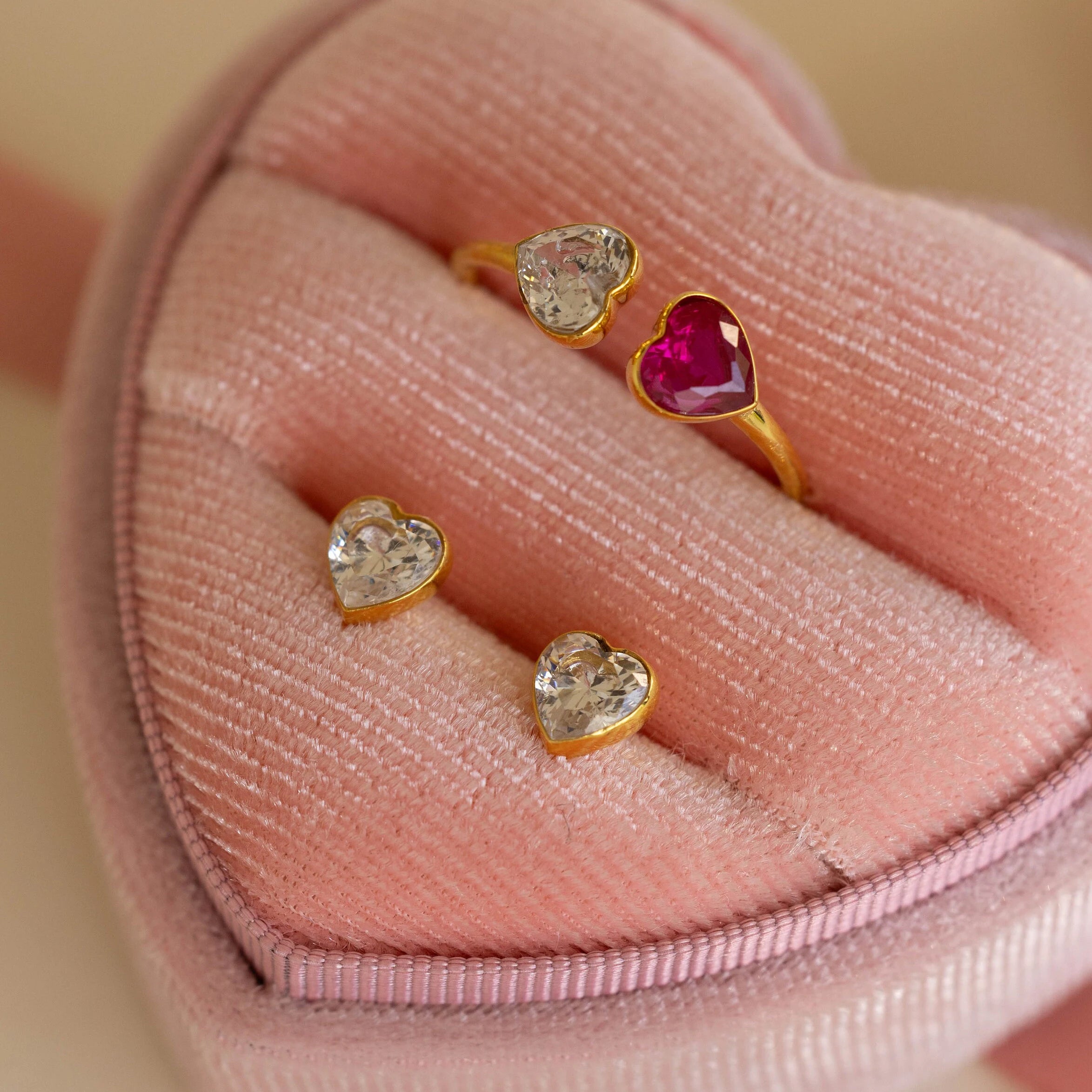 Bezel Heart Birthstone Studs with sparkling, heart-shaped stones are elegantly presented in a pink velvet heart-shaped jewelry box.