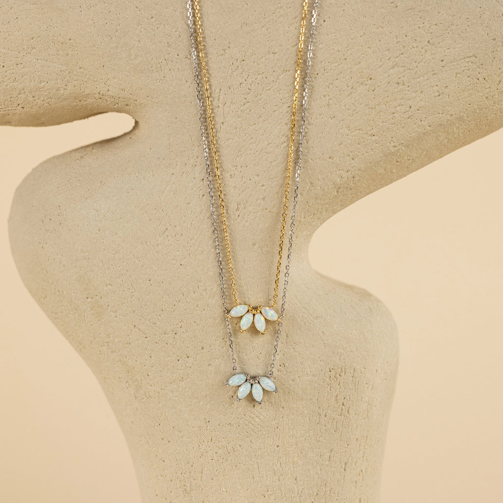 The display features two delicate necklaces with leaf-shaped pendants, including the White Opal Marquise Necklace, arranged gracefully on an abstract beige stand.