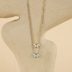 The display features two delicate necklaces with leaf-shaped pendants, including the White Opal Marquise Necklace, arranged gracefully on an abstract beige stand.