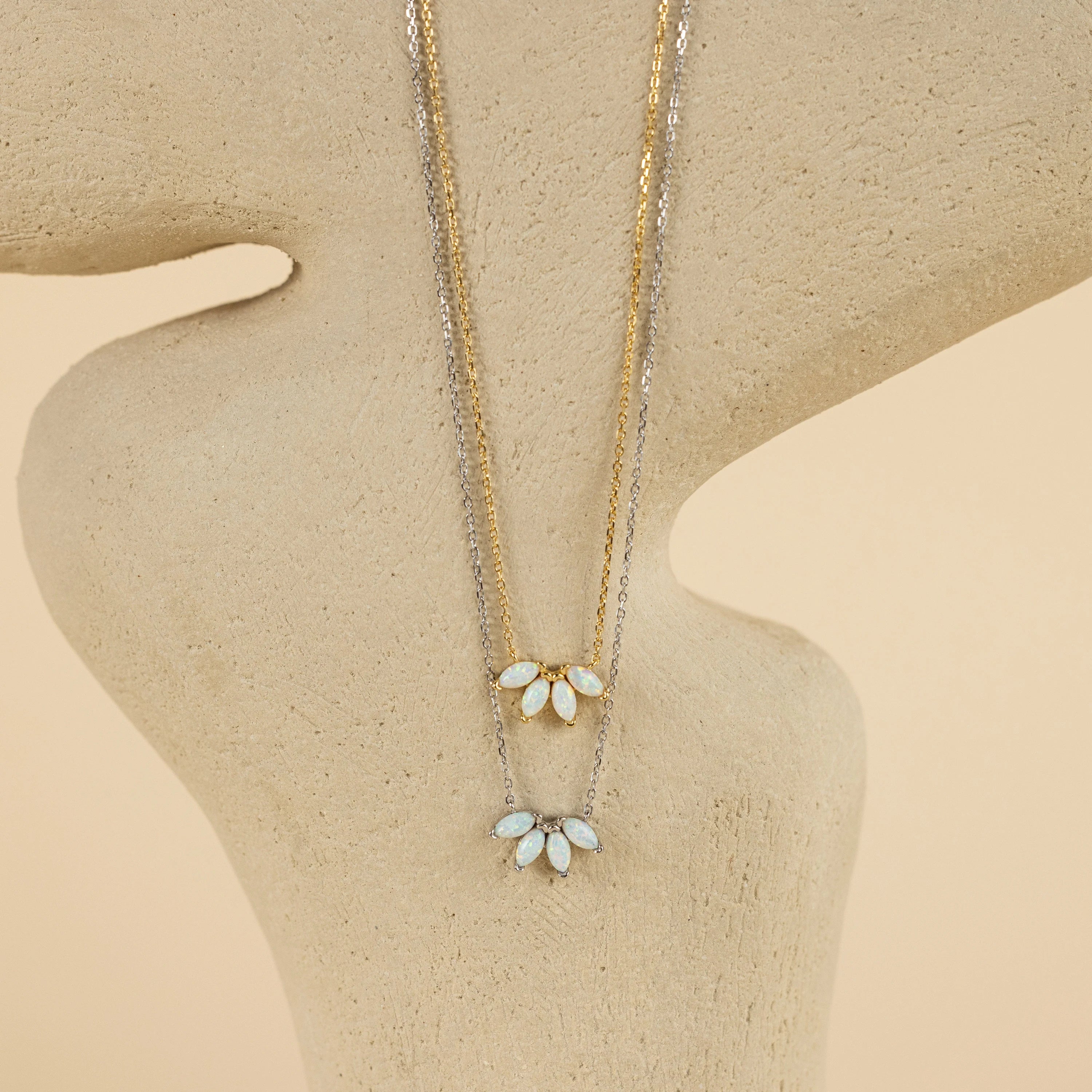 The display features two delicate necklaces with leaf-shaped pendants, including the White Opal Marquise Necklace, arranged gracefully on an abstract beige stand.