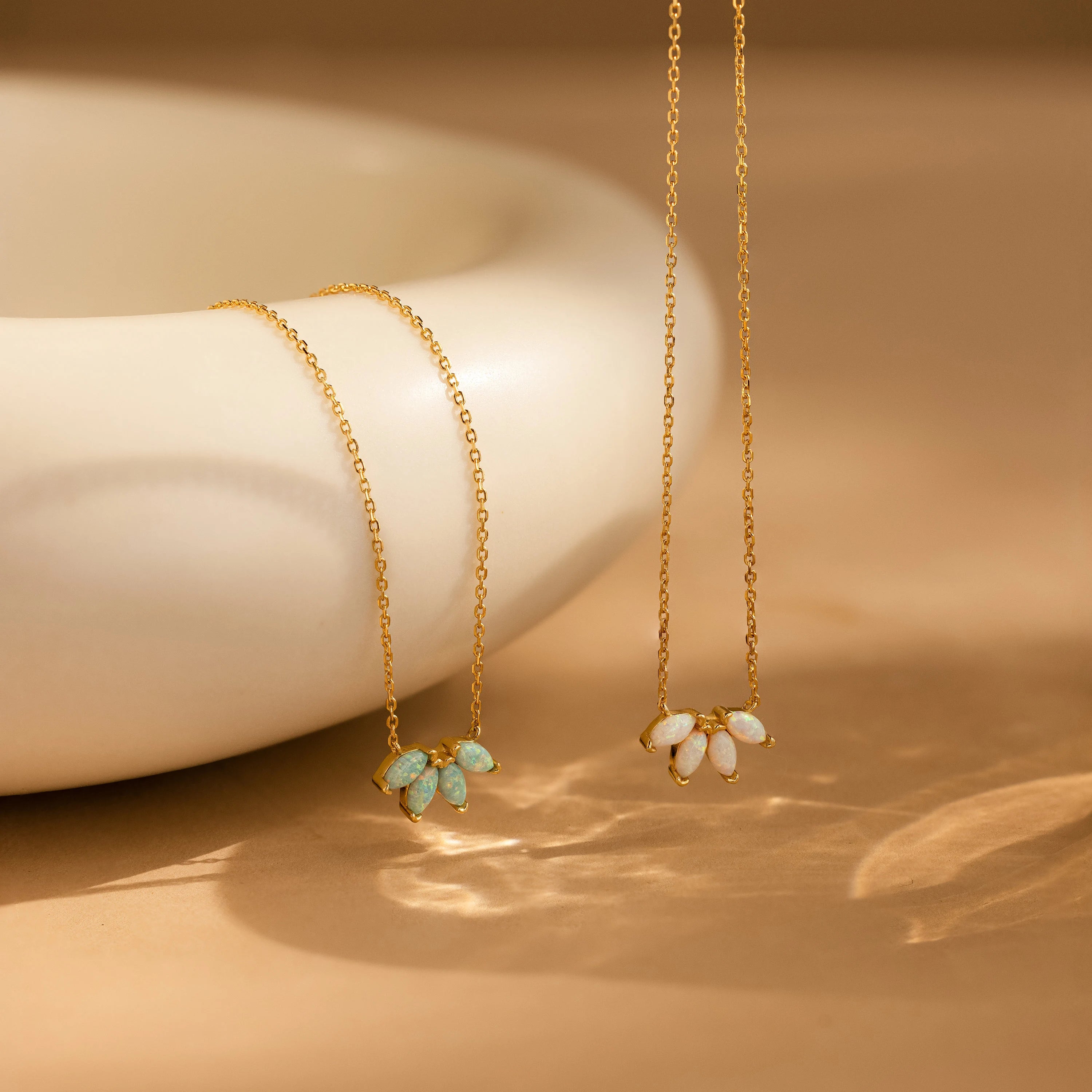 A White Opal Marquise Necklace with elegant clusters is displayed beside a smooth, cream-colored ceramic bowl.