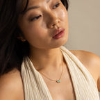 Woman in a cream halter top wearing the Turquoise Opal Marquise Necklace, looking thoughtfully to the side.