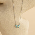 Turquoise Opal Marquise Necklace featuring four small blue-green opal stones, elegantly displayed on a cream textured background.