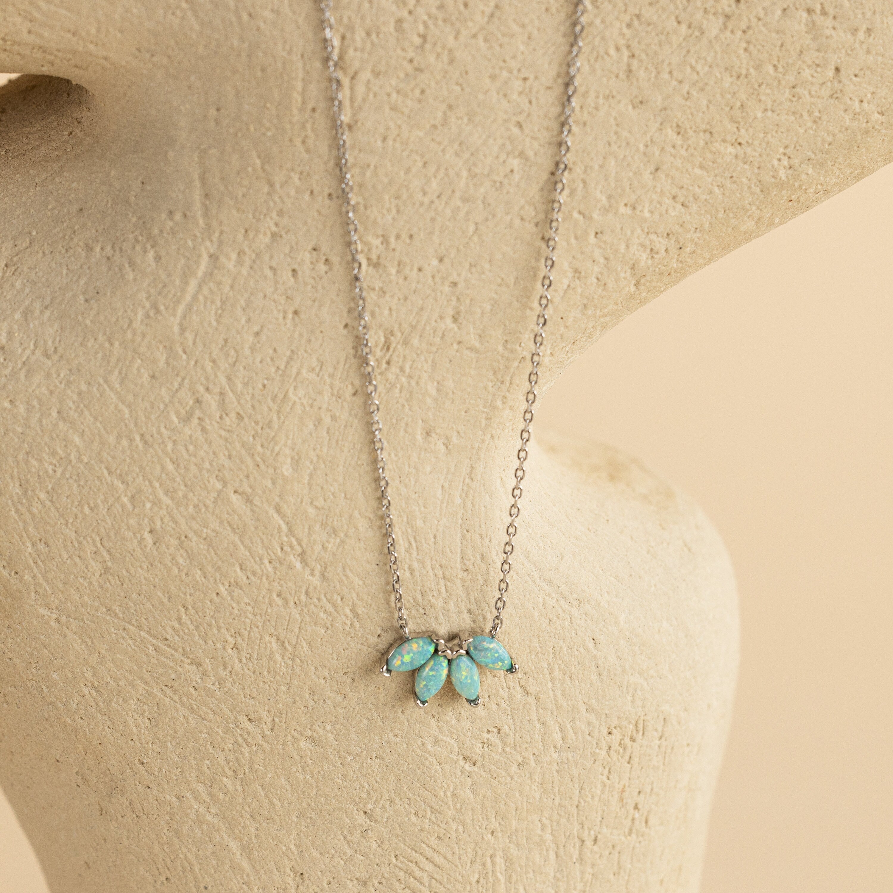 Turquoise Opal Marquise Necklace featuring four small blue-green opal stones, elegantly displayed on a cream textured background.