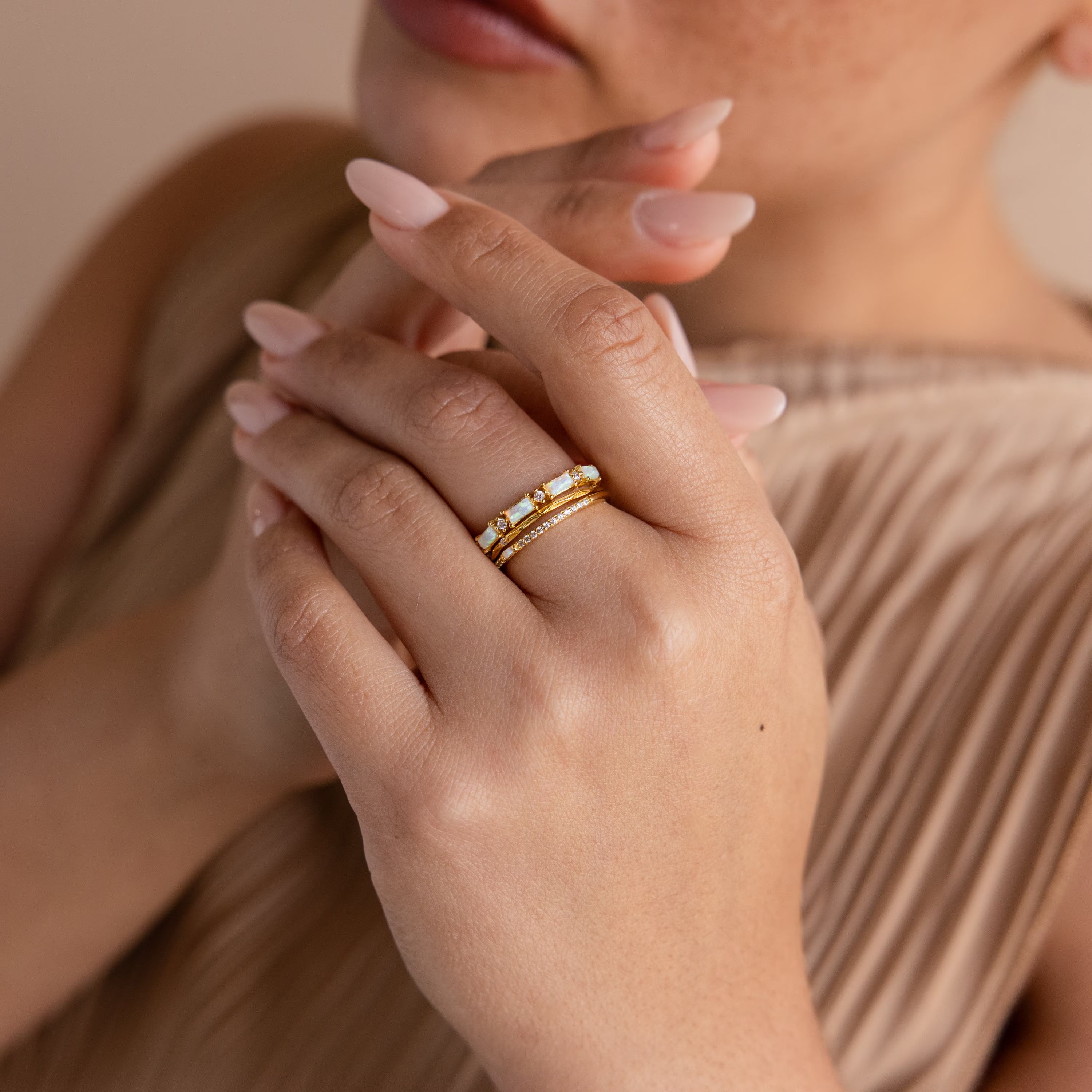 A woman with manicured nails wears the Pave Opal Ring Set in 18K Gold, holding her hands together near her face.