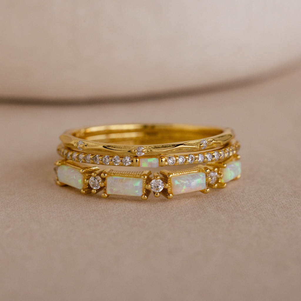 The Pave Opal Ring Set in 18K Gold features two stacked bands with rectangular opals and round diamonds, offering an elegant, timeless look on a soft beige background.