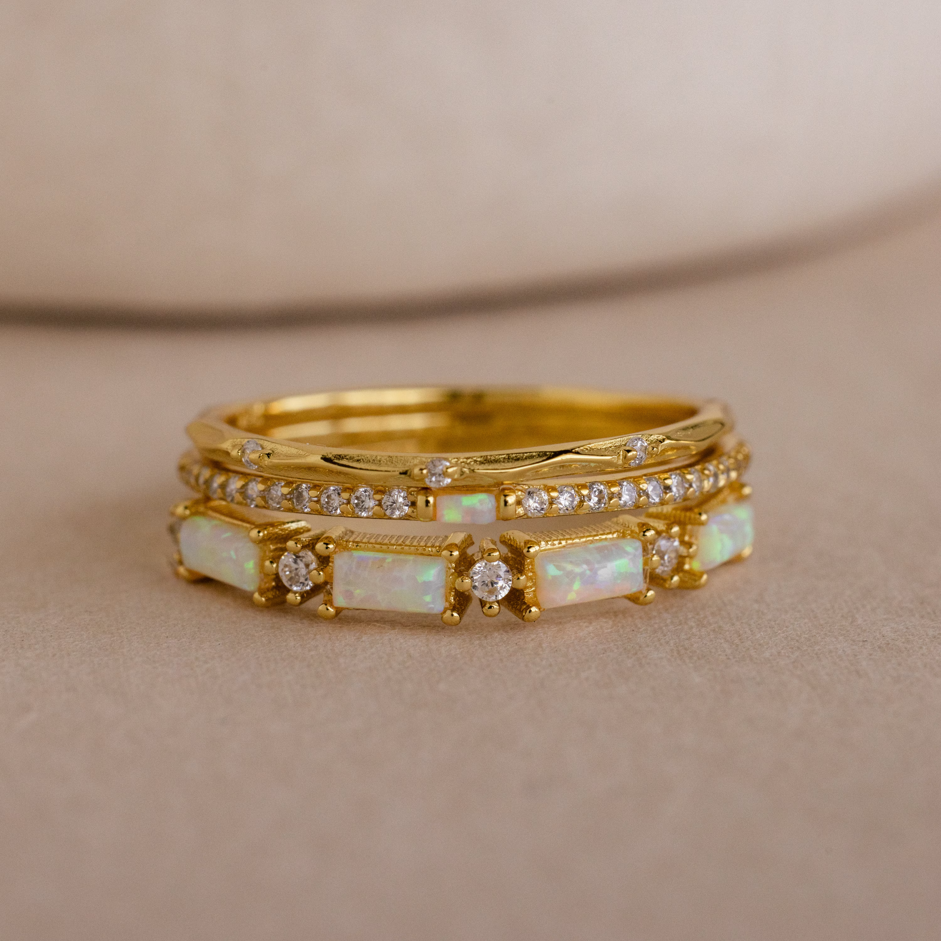 The Pave Opal Ring Set in 18K Gold features two stacked bands with rectangular opals and round diamonds, offering an elegant, timeless look on a soft beige background.