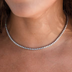 A close-up of a woman's neck wearing the Opal Bezel Tennis Necklace, highlighting the necklace's elegant opal accents and iridescent charm.