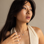 Woman with long dark hair wearing a cream halter top and the Pave Pearl North Star Necklace, looking to the side.
