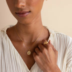 A woman wearing a gold necklace and the North Star Signet Ring.