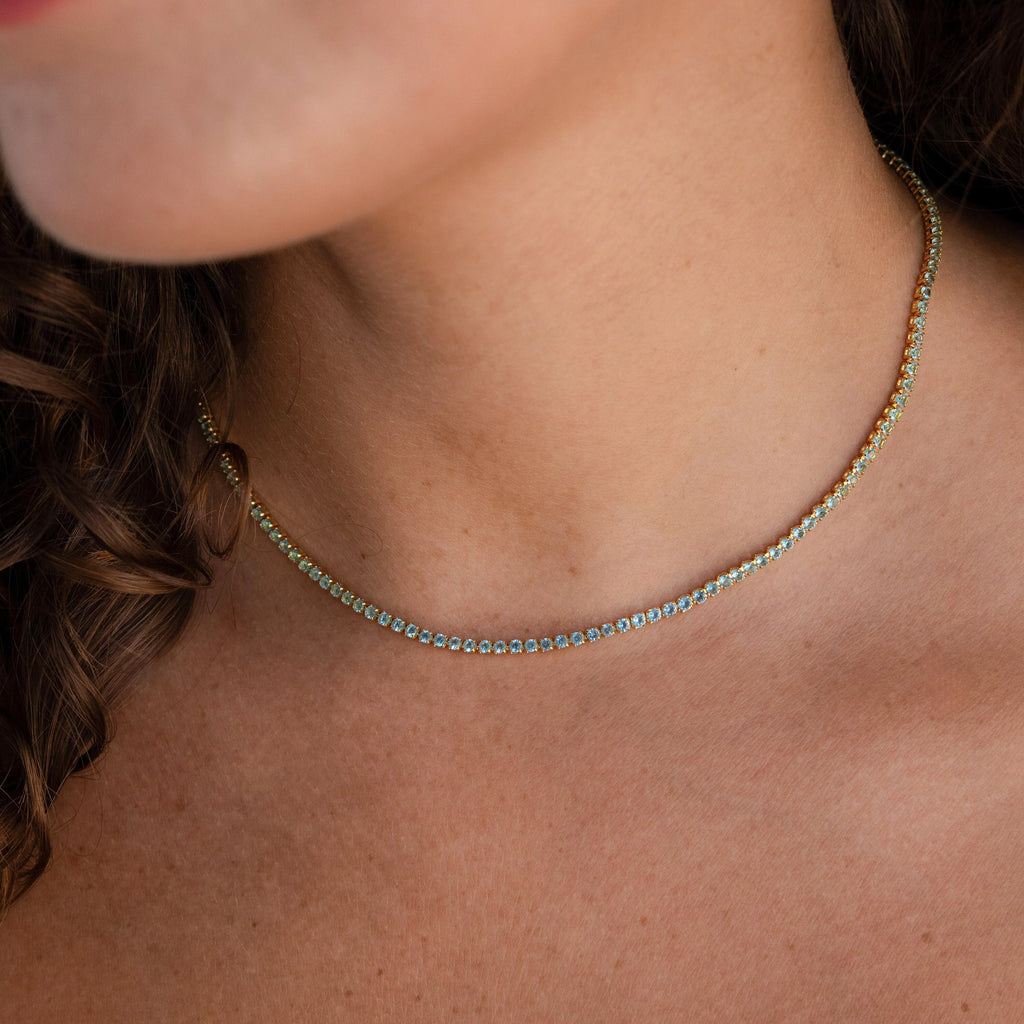 Close-up of a woman's neck adorned with the Aquamarine Tennis Choker Necklace—an elegant gold and turquoise piece, perfect for wedding jewelry or as a bridal accessory.