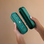 Hands holding an open Slim Velvet Ring Box on a beige background, showcasing multiple gold and gemstone rings—an elegant organizer and jewelry case for displaying your favorite pieces.