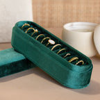 The Slim Velvet Ring Box showcases elegant gold rings, with a candle and ceramic bowl softly blurred in the background.