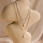 The Duo Chain Pearl Necklace features two elegant layers of pearls with gold and silver accents, stylishly displayed on a beige abstract mannequin bust.