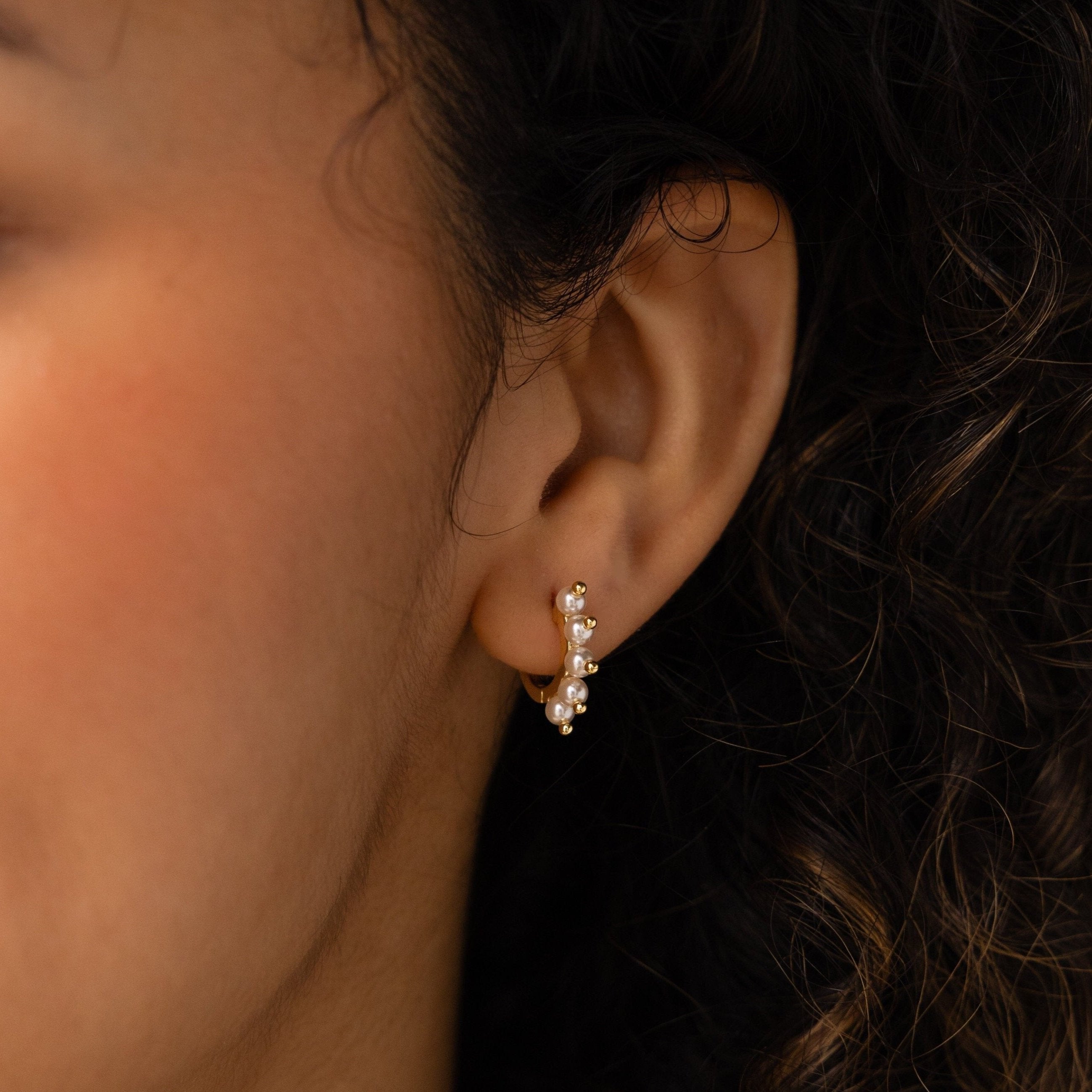 Close-up of a woman's ear wearing Beaded Pearl Huggies, featuring a modern design with delicate small pearls.