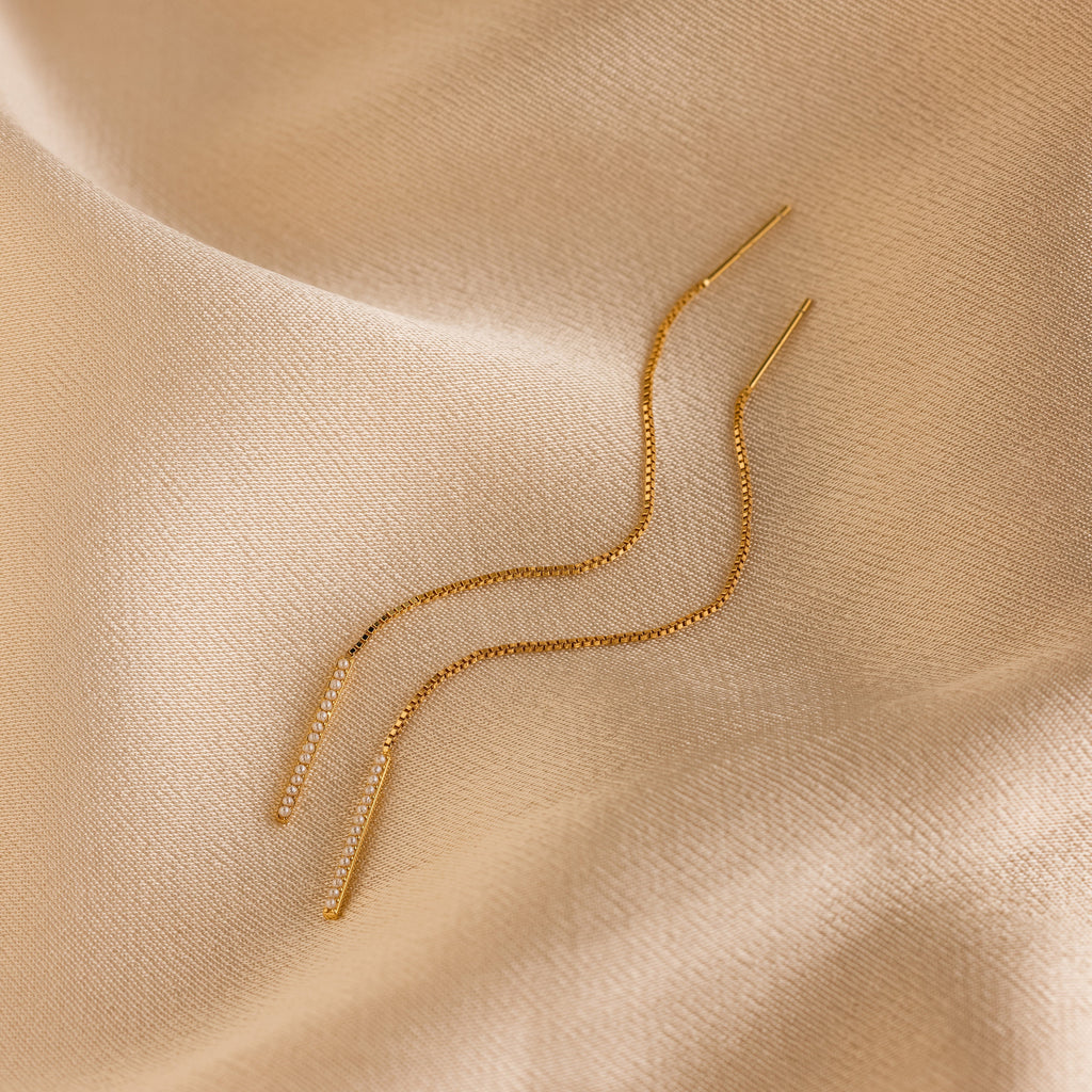 Pearl Bar Threader Earrings displayed on smooth beige satin fabric, these dainty earrings bring modern elegance to any look—a must-have pearl jewelry essential.