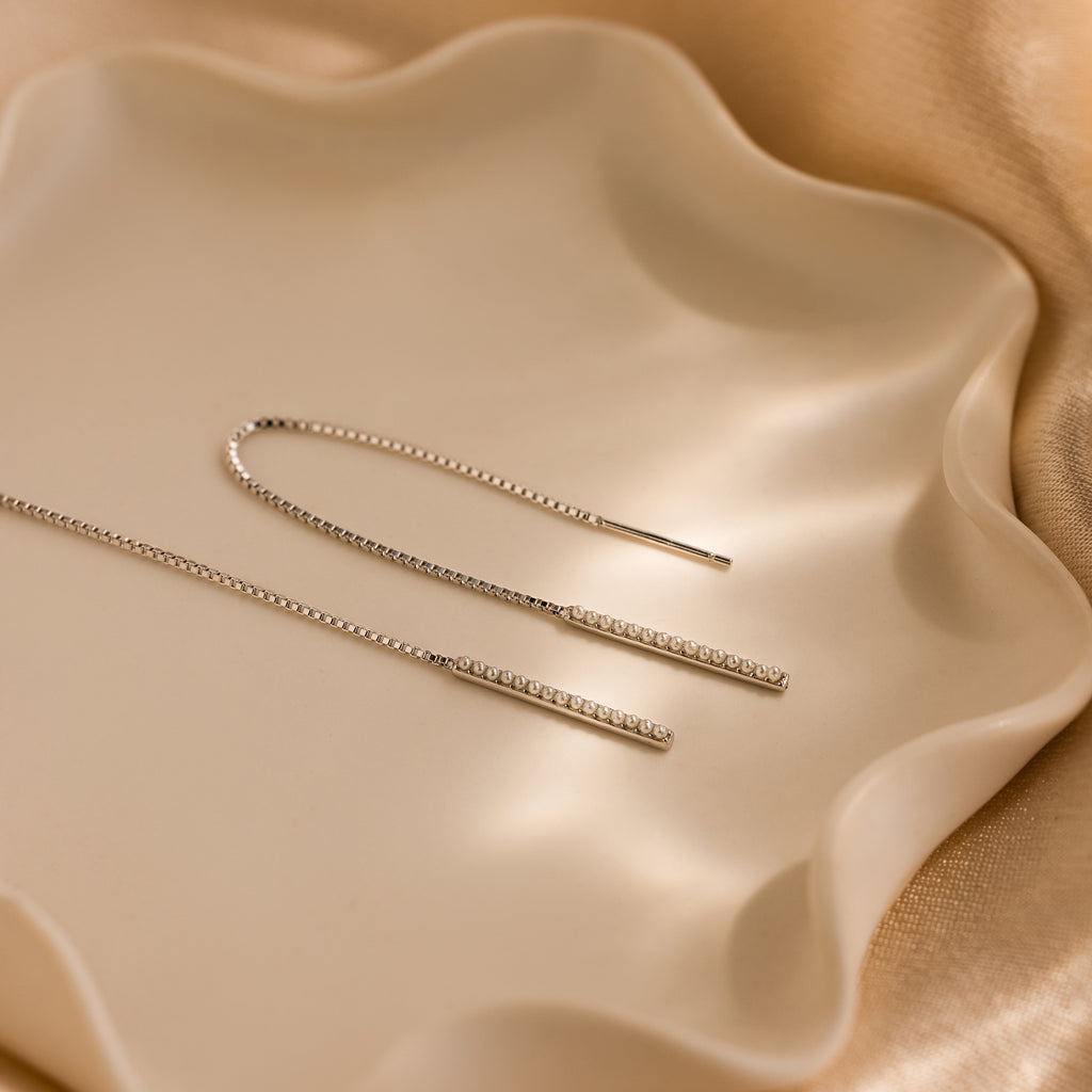 Pearl Bar Threader Earrings showcased on a wavy-edged cream dish with a satin backdrop—an elegant pick for those who love dainty and modern pearl jewelry.