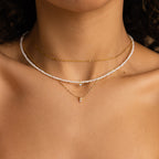 Close-up of a woman's neck showcasing the Pearl & Diamond Duo Necklace, elegantly layered with a pearl choker and gold chain featuring a diamond pendant.