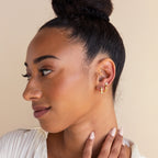 Woman with a bun hairstyle wears celestial Moonstone Star Studs, looking to the side and gently touching her neck.