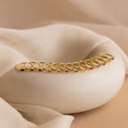 A row of gold rings, including the Marquise Bezel Birthstone Ring with colorful gemstones, displayed on a smooth white curved surface with fabric drapes.