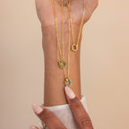 A hand with manicured nails displays three Interlocking Birthstone Necklaces, each featuring colorful circular pendants—meaningful keepsake jewelry and a thoughtful gift for mom.