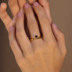 A hand with light pink nails wears three stacked gold rings from the Black Diamond Rings Set, creating a chic layered jewelry look.