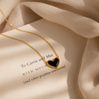 The Pave Onyx Puff Heart Necklace in 18K Gold features an onyx heart pendant and is displayed atop a page printed with a heartfelt message.