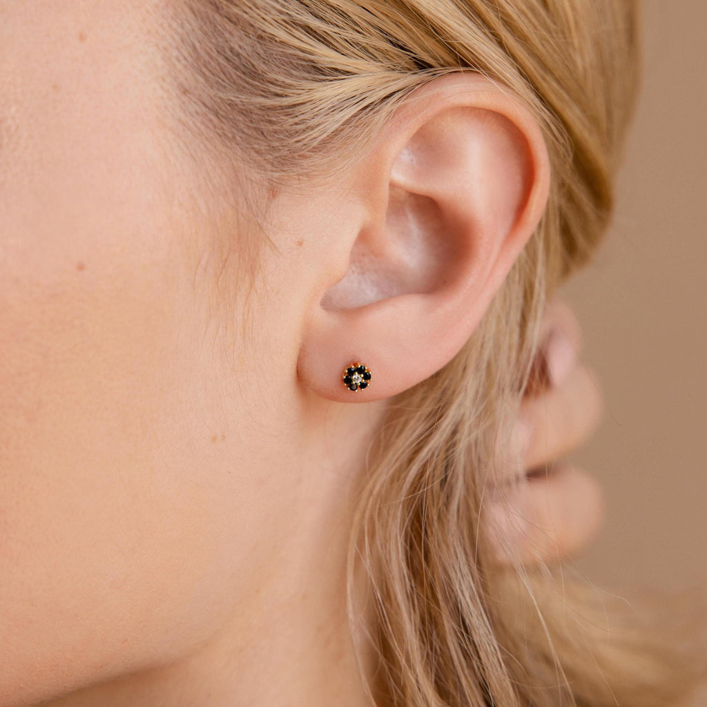 Close-up of a woman's ear adorned with Onyx Flower Studs—small, round earrings featuring black onyx and gold accents—highlighting the refined elegance of flatback earrings.