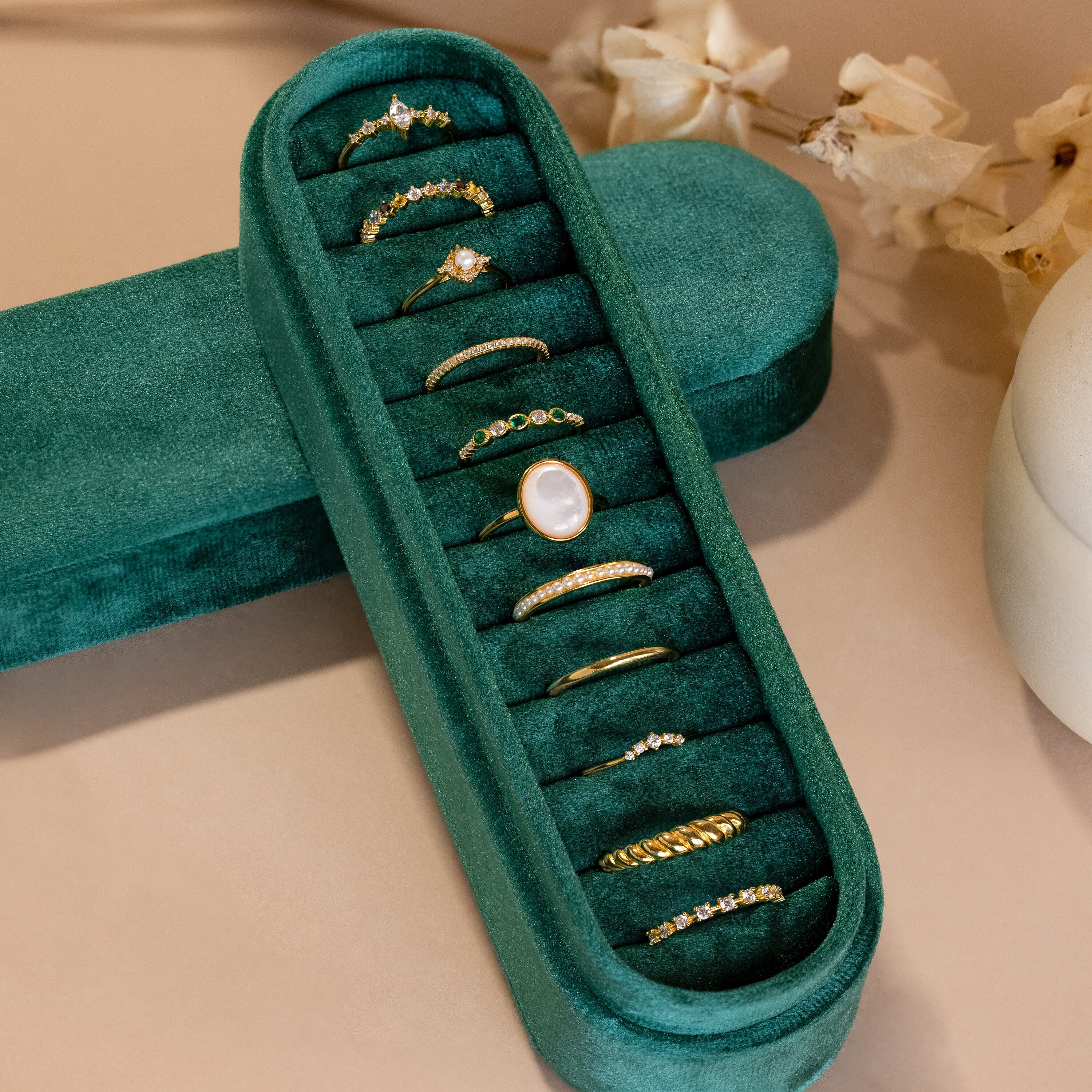 Ten gold rings with assorted gemstones are arranged in a Slim Velvet Ring Box, elegantly organizing the collection on a beige surface.