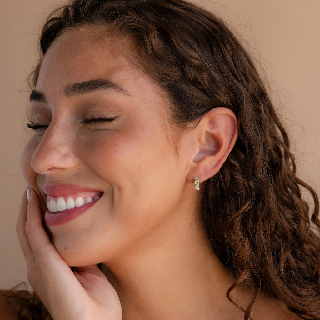 A woman with her eyes closed wears Ombre Opal Huggies, their gentle shimmer accentuating her serene beauty.