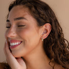 A woman with her eyes closed wears Ombre Opal Huggies, their gentle shimmer accentuating her serene beauty.