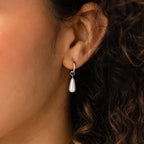 A close-up shows someone wearing Pearl Teardrop Huggies—silver hoops with dangling teardrop pearls, ideal for bridal or beach wedding styles.