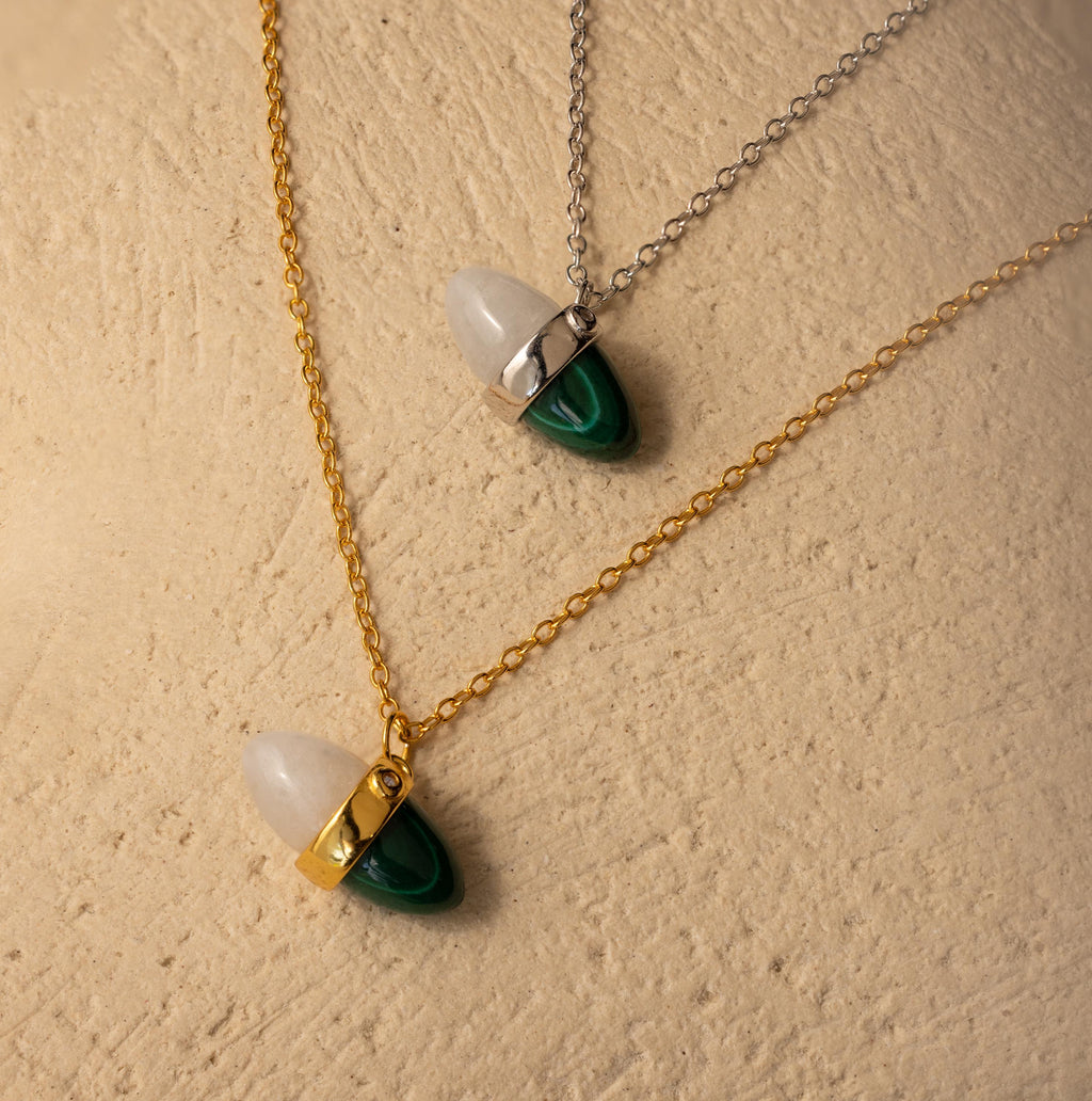 The Malachite & Moonstone Necklace features gold and silver chains with white moonstone and green malachite charms—ideal for gemstone jewelry lovers.