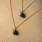 The Malachite & Moonstone Necklace features gold and silver chains with white moonstone and green malachite charms—ideal for gemstone jewelry lovers.