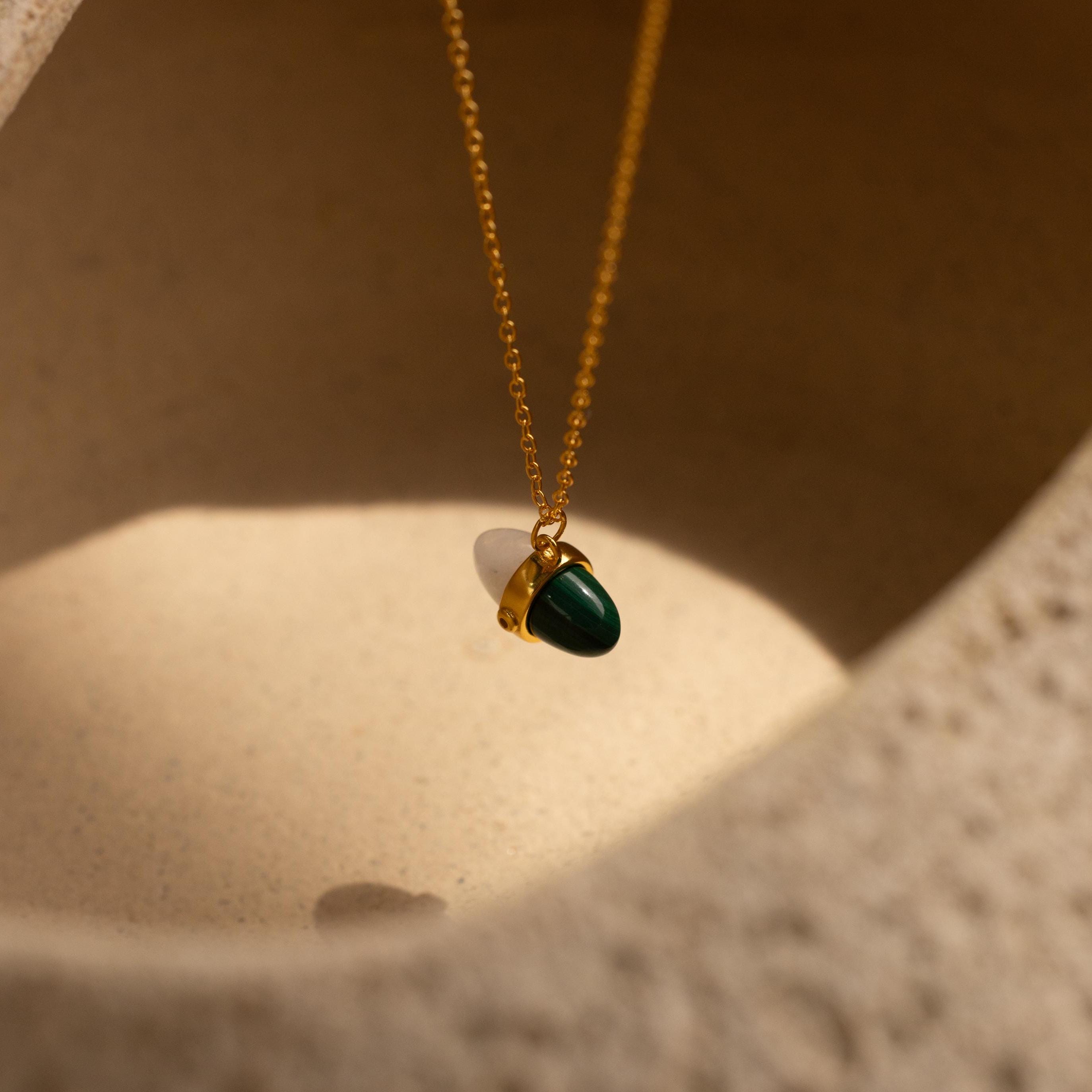 Malachite & Moonstone Necklace featuring a delicate green stone pendant, elegantly set against a textured beige background in soft light—a stunning piece that captures the essence of healing gemstone jewelry.