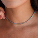 A close-up of a person wearing the Turquoise Bezel Tennis Necklace, featuring delicate bezels set with small turquoise stones.