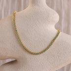 The Turquoise Bezel Tennis Necklace, featuring gold and turquoise stones, is displayed on a textured off-white mannequin bust.